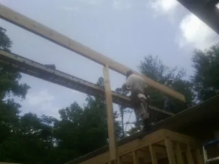 Carpenter setting a ridge beam over a new addition frame — Ice Dam Removal by Roofing Brothers in Kinsale