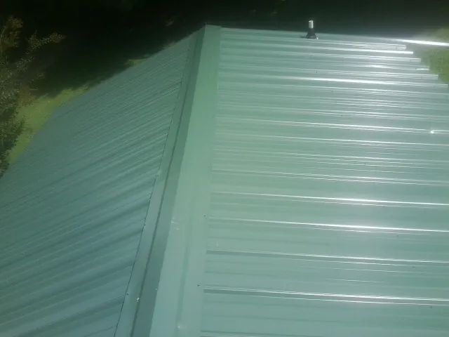 New green metal panels meeting at the ridge of a roof — Flat Roof Repair work by our crew in Kinsale
