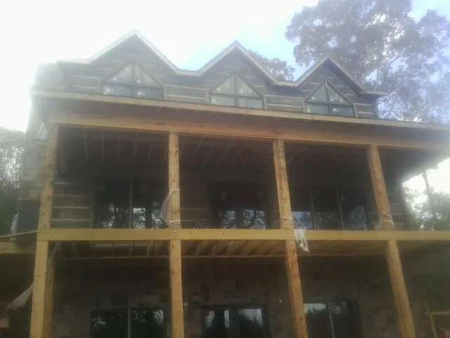 Dormers and porch framing on a large log home under construction — Roof Coating work by our crew in Kinsale