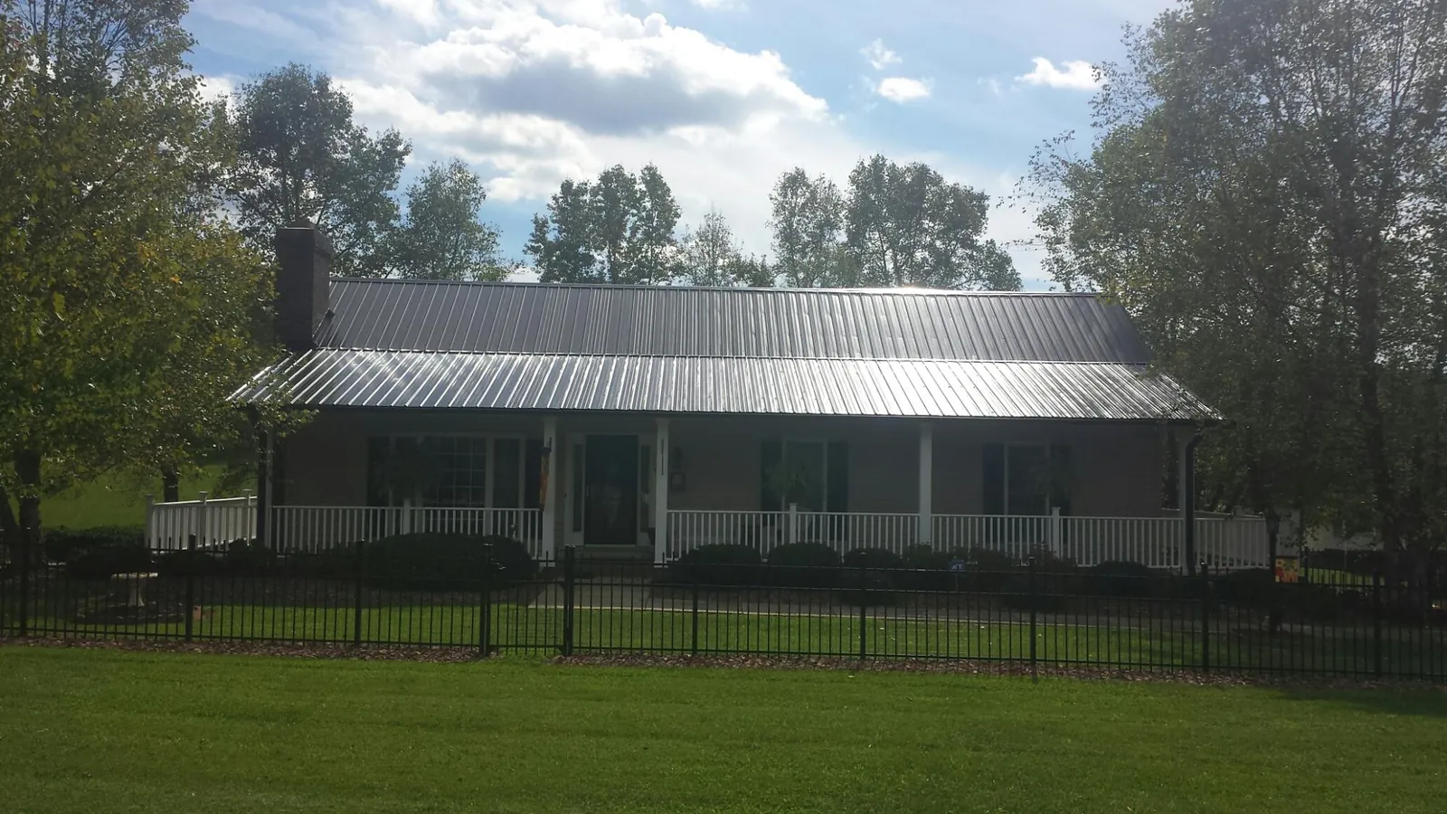 Gray metal roof on a brick ranch with a full width front porch — Gutter Guard Installation work by our crew in Kinsale