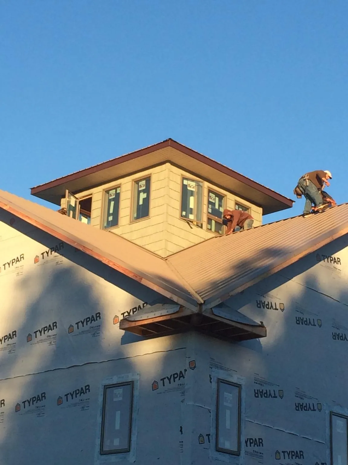 Roofers working around a rooftop cupola on a new metal roof at sunset — Roof Waterproofing in Kinsale by Roofing Brothers